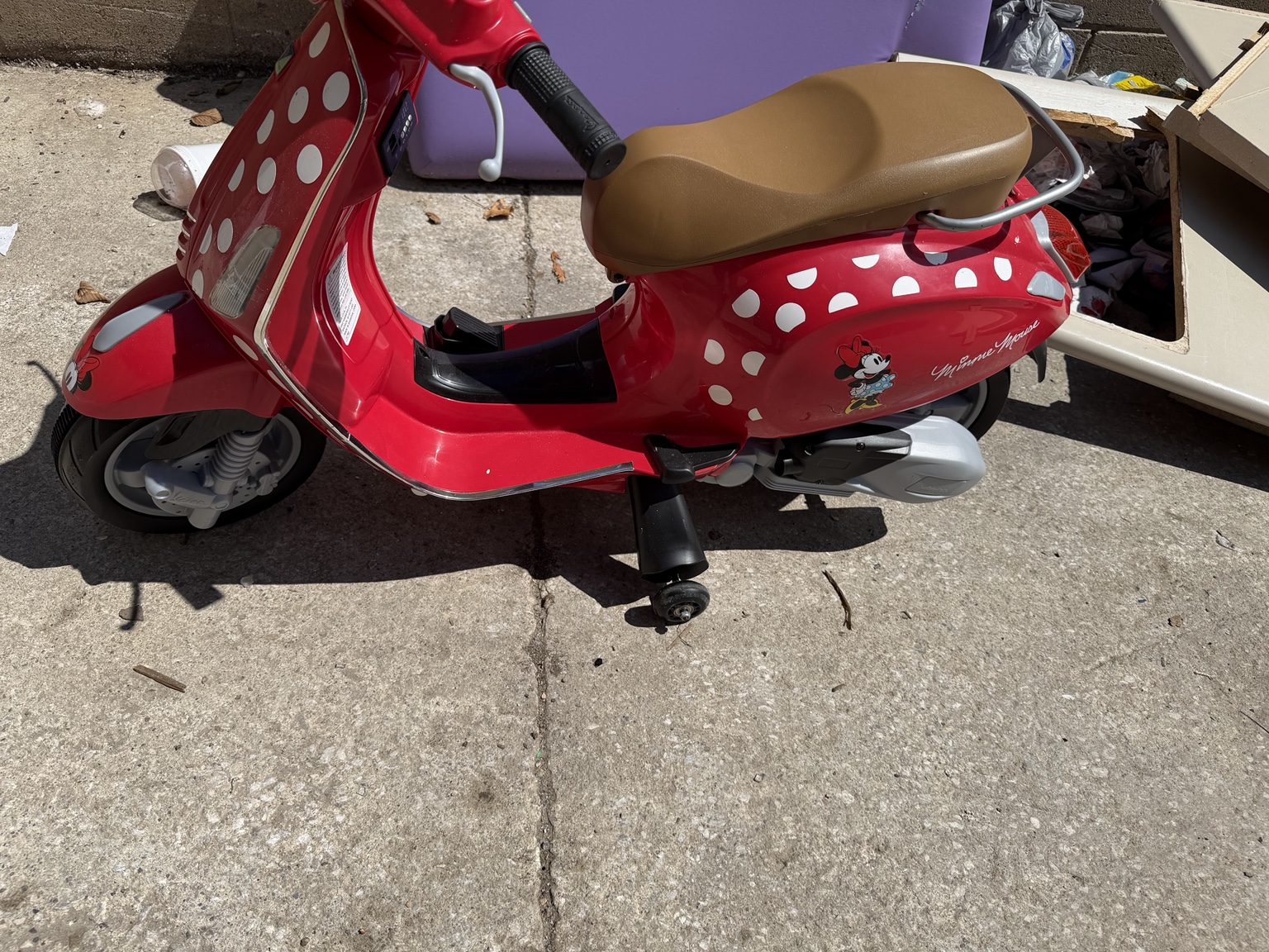 A child's red ride-on scooter in good condition set out in the Waggoner Park bulk area beside usable furniture